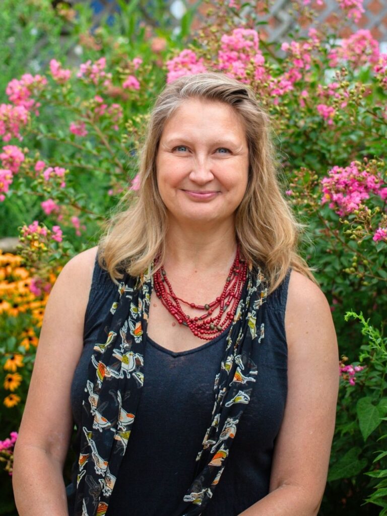 Staff member pictured in front of flower bushes on the Horizon Academy campus.