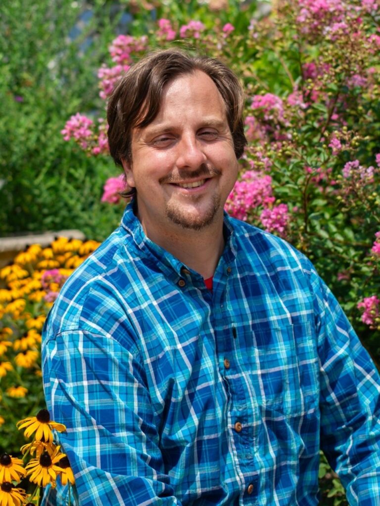 Staff member pictured in front of flower bushes on the Horizon Academy campus.