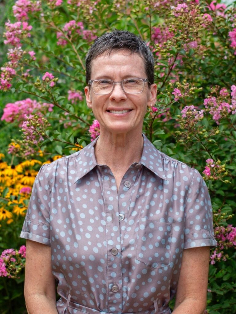 Staff member pictured in front of flower bushes on the Horizon Academy campus.