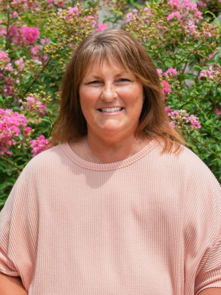 Staff member pictured in front of flower bushes on the Horizon Academy campus.
