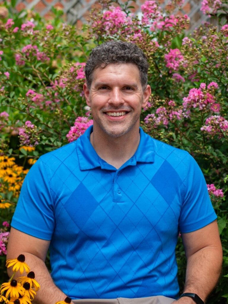 Staff member pictured in front of flower bushes on the Horizon Academy campus.