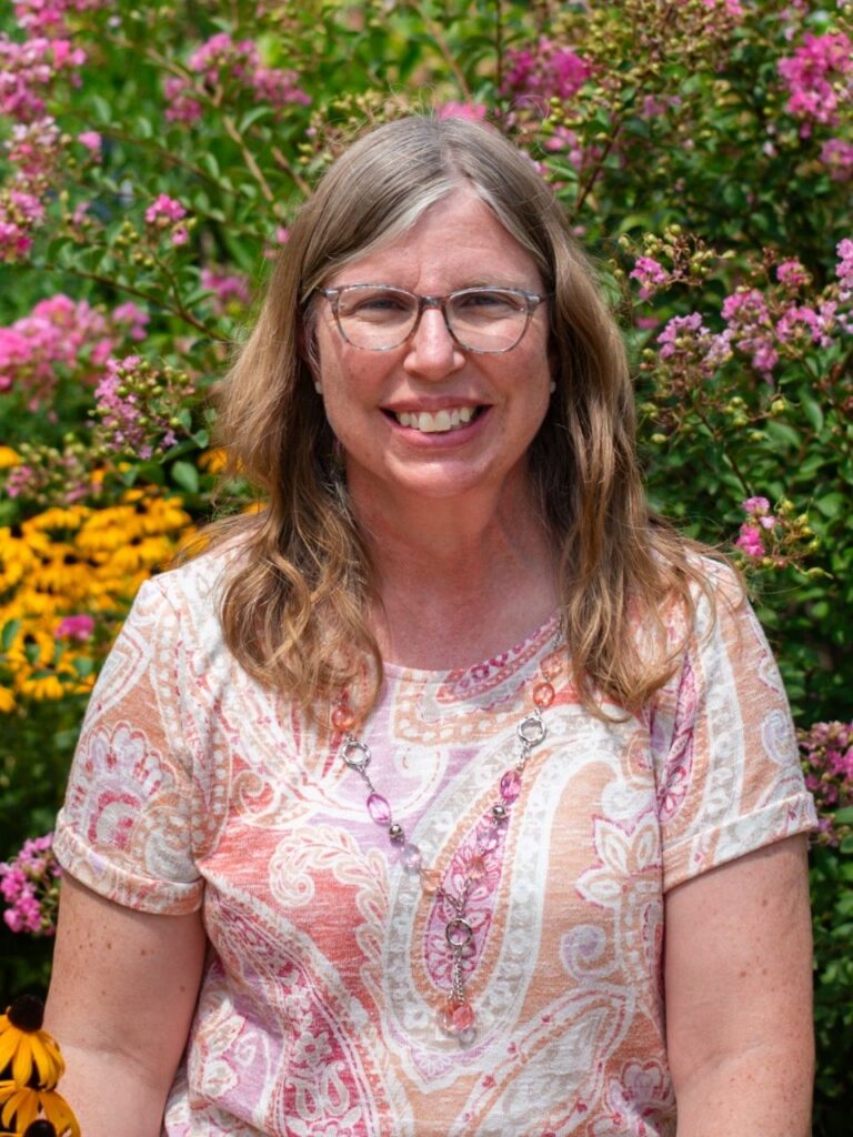 Staff member pictured in front of flower bushes on the Horizon Academy campus.