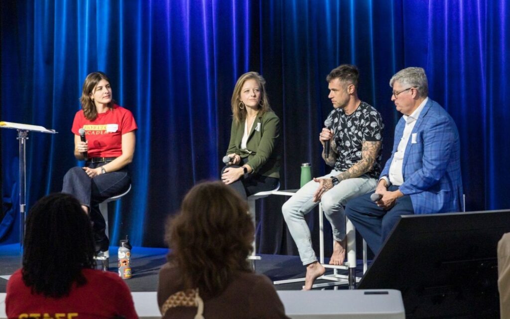 Four Brilliantly Wired panelists sit onstage before blue curtains. Their relaxed, attentive expressions create a thoughtful, conversational atmosphere.
